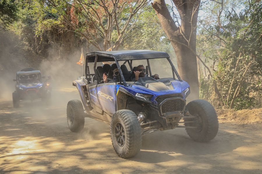 Polaris RZR driving dusty trails surrounded by nature.