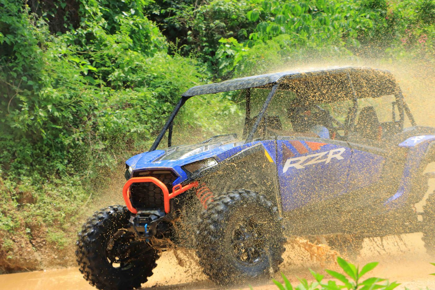 Polaris RZR splashing through muddy trails during an off-road tour in Puerto Vallarta